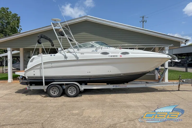 Slide: The Image of 2000 Sea Ray Sundancer 260 boat on trailer, parked outside a building under clear skies. - 19