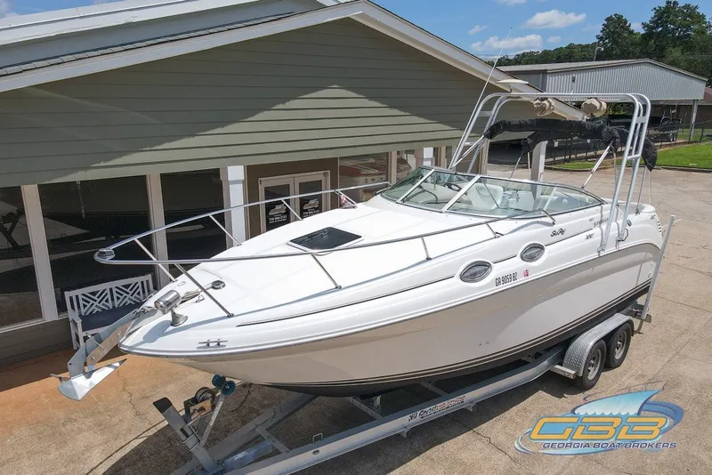 Slide: The Image of 2000 Sea Ray Sundancer 260 on trailer, parked outside a building. - 1