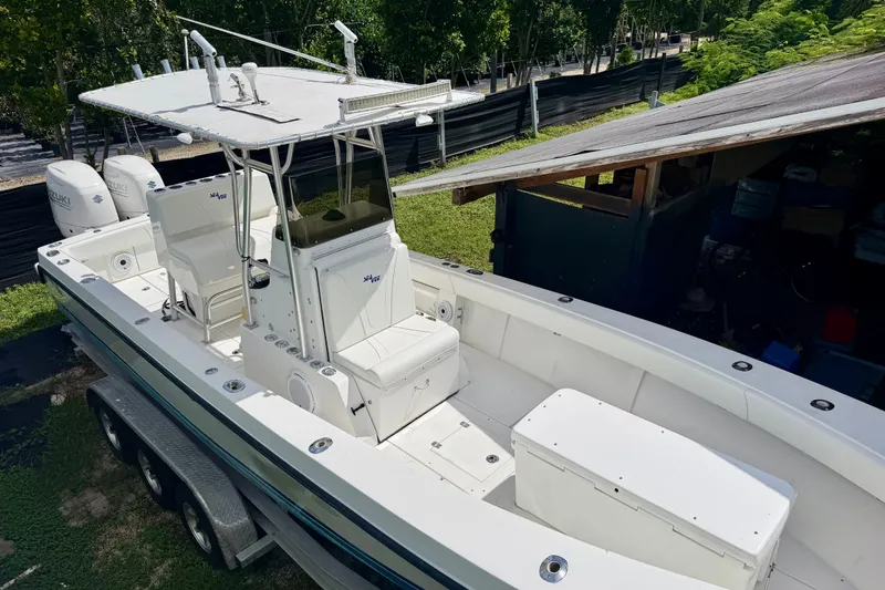 Slide: The Image of 2001 SeaVee 290B boat with dual Suzuki engines, parked on a trailer near greenery. - 3