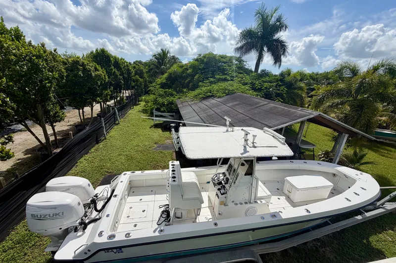 The Image of 2001 SeaVee 290B boat with Suzuki engines, parked on grass under a sunny sky. - 1