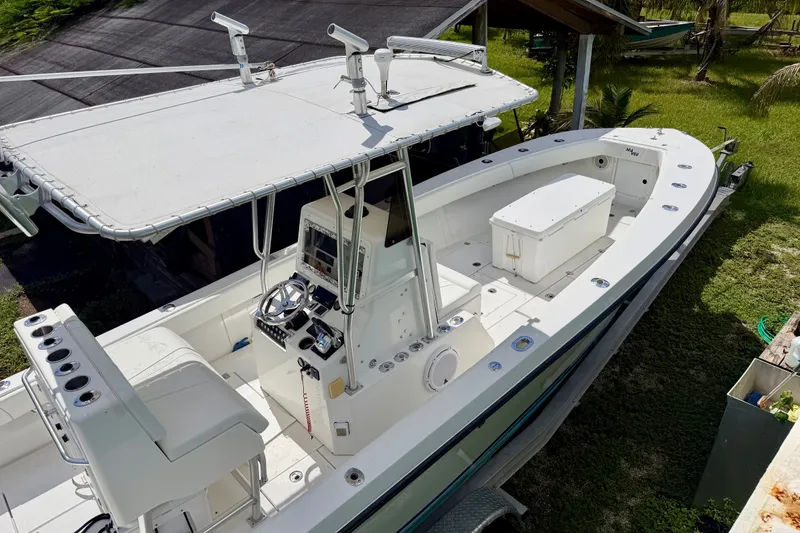 Slide: The Image of 2001 SeaVee 290B boat with center console and T-top, docked on grass. - 2