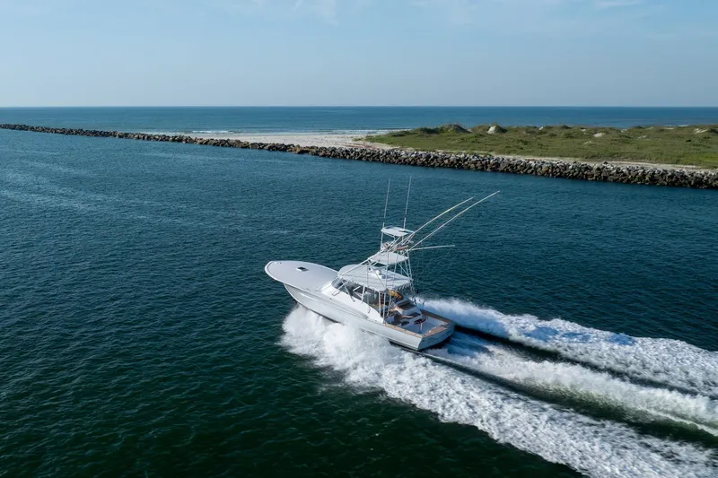 Slide: The Image of Custom Carolina East Bay 2001 yacht cruising on open water near a rocky shoreline. - 61