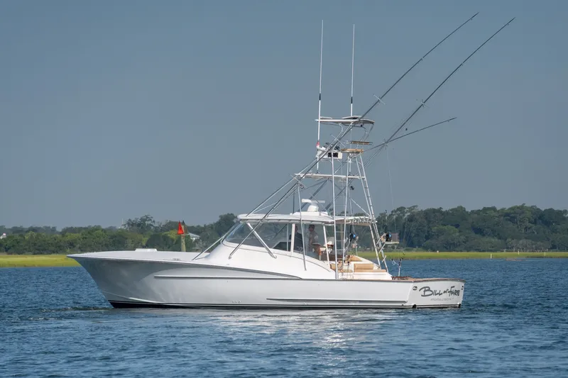 Slide: The Image of 2001 Custom Carolina East Bay boat on calm water, featuring fishing rods and a sleek design. - 7