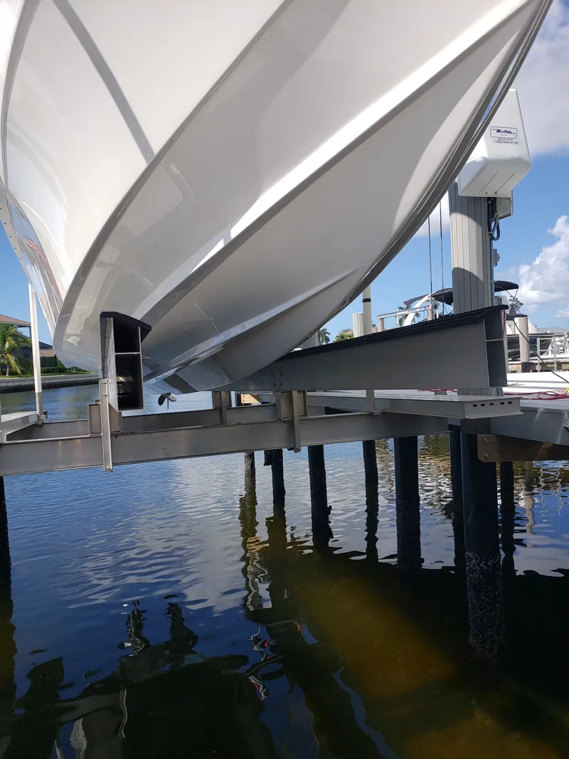 Slide: The Image of A white boat on a boat lift above the water, with a clear sky in the background. - 11