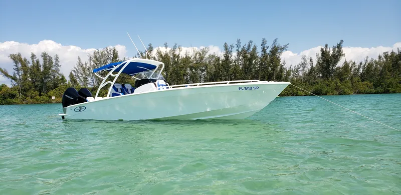 The Image of A white open deck boat floats in clear water, surrounded by trees in the background. - 0