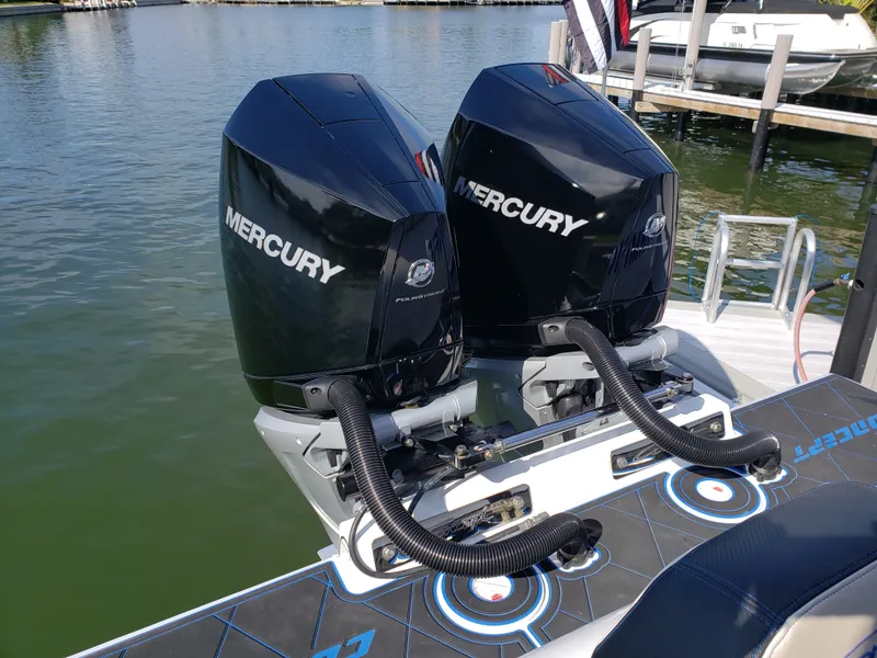 Slide: The Image of Two Mercury outboard engines are mounted on the stern of a boat docked in the water. - 26