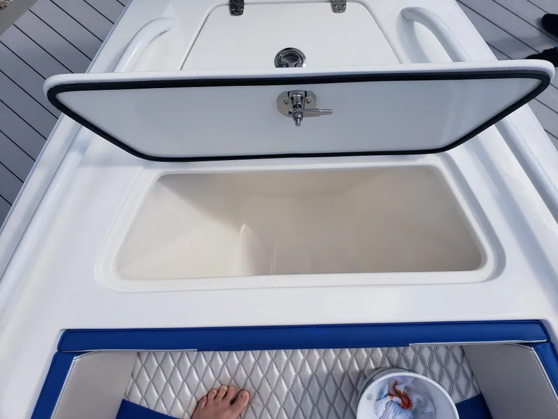 Slide: The Image of An open storage compartment on a boat with blue upholstery and a bucket nearby. - 2