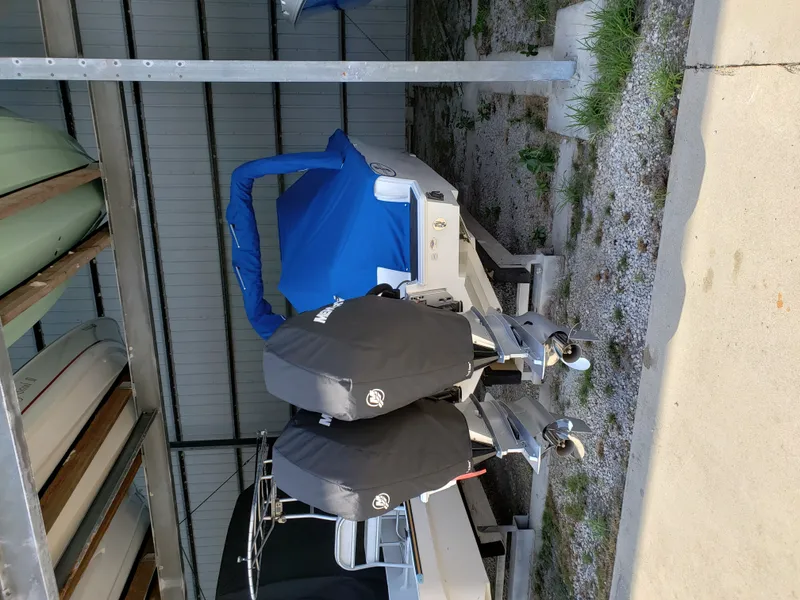 Slide: The Image of A white boat with a blue cover is stored in a warehouse. Two engines are mounted at the rear. - 24