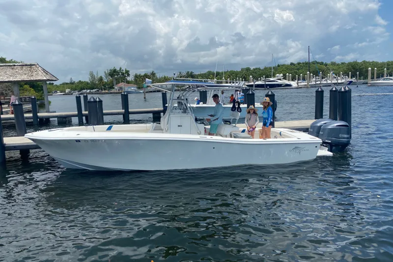 Slide: The Image of A 2000 Ocean Runner 27 boat docked with people onboard, under a partly cloudy sky. - 1
