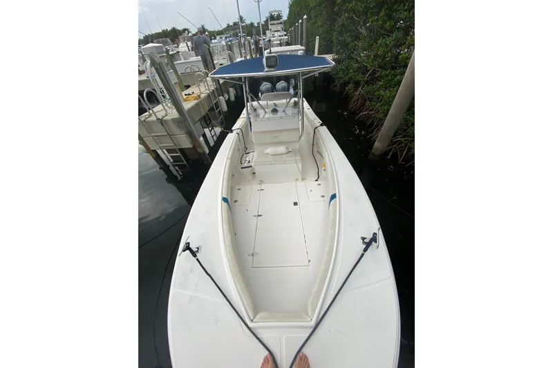 Slide: The Image of 2000 Ocean Runner 27 boat docked, featuring a spacious deck and blue canopy. - 2