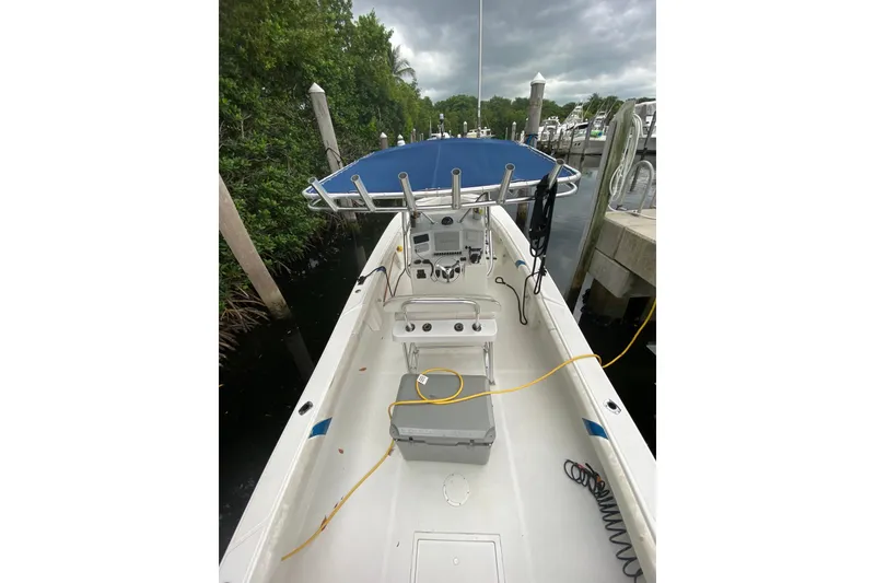 Slide: The Image of 2000 Ocean Runner 27 boat docked, featuring a blue canopy and spacious deck. - 18