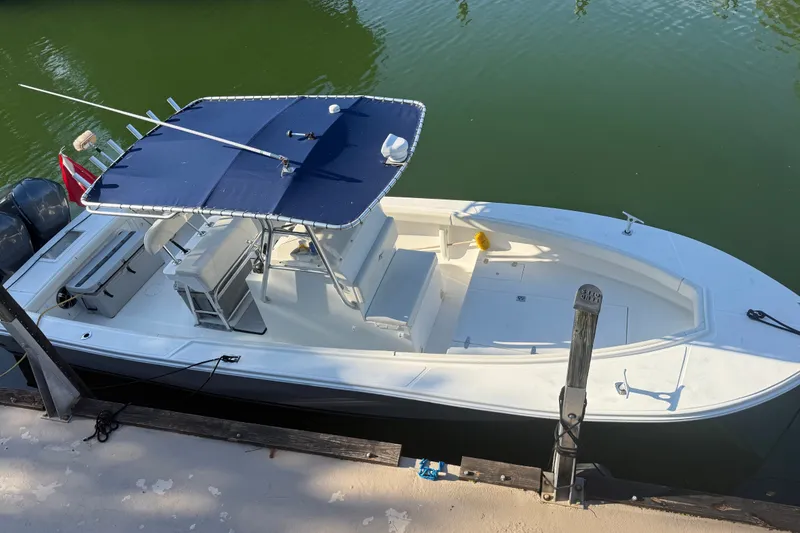 Slide: The Image of 2000 Ocean Runner 27 boat docked, featuring a blue canopy and twin engines. - 9