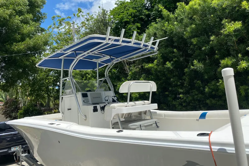 Slide: The Image of 2000 Ocean Runner 27 boat with blue canopy, parked outdoors amidst lush greenery. - 7