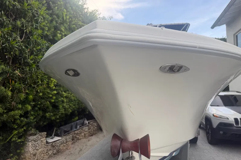 Slide: The Image of Front view of a 2000 Ocean Runner 27 boat, parked near greenery and a vehicle. - 19