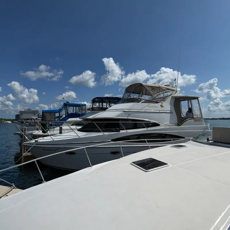 The Image of A 2002 Carver 366 Motor Yacht is docked in the water, surrounded by other boats under a blue sky. - 1