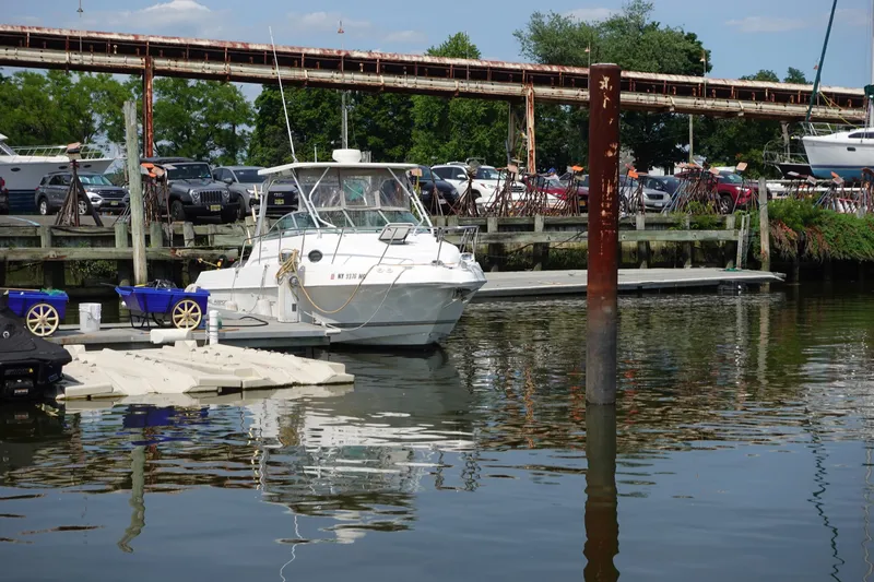 Slide: The Image of 2004 Grady-White Tournament 275 boat docked at a marina with parked cars in the background. - 5