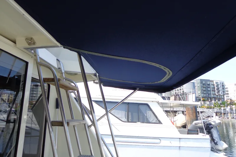 Slide: The Image of 1989 Tollycraft 34 Sport Sedan with blue canopy and marina view. - 47