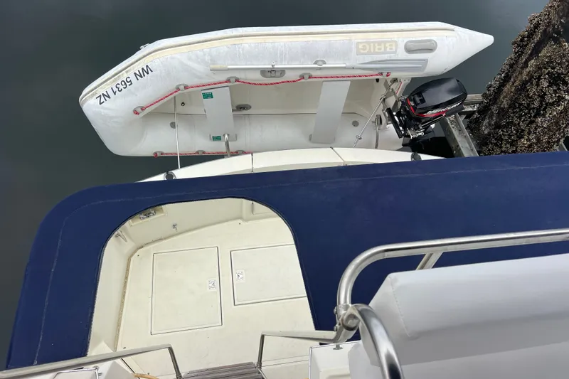 Slide: The Image of 1989 Tollycraft 34 Sport Sedan with dinghy and outboard motor, docked at marina. - 34
