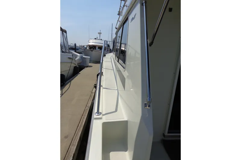 Slide: The Image of 1989 Tollycraft 34 Sport Sedan docked, showcasing sleek side deck and railing. - 55