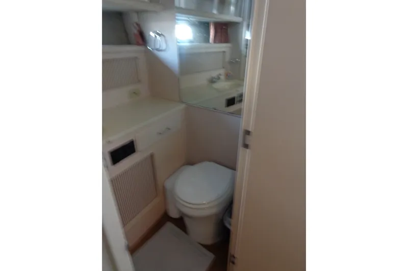 Slide: The Image of 1989 Tollycraft 34 Sport Sedan bathroom with toilet, sink, and storage shelves. - 25