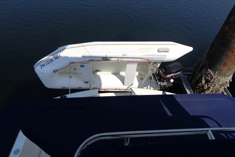 Slide: The Image of 1989 Tollycraft 34 Sport Sedan with dinghy and outboard motor docked by a pier. - 50