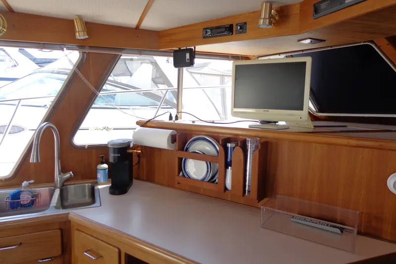 Slide: The Image of 1989 Tollycraft 34 Sport Sedan interior with kitchen sink, TV, and wooden cabinetry. - 37