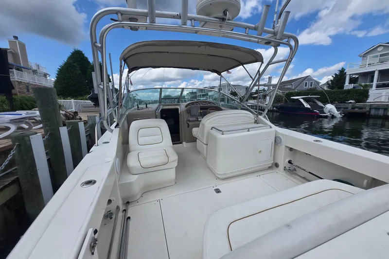 Slide: The Image of 2000 Sea Ray 290 Amberjack boat interior with seating and helm, docked by waterfront homes. - 6