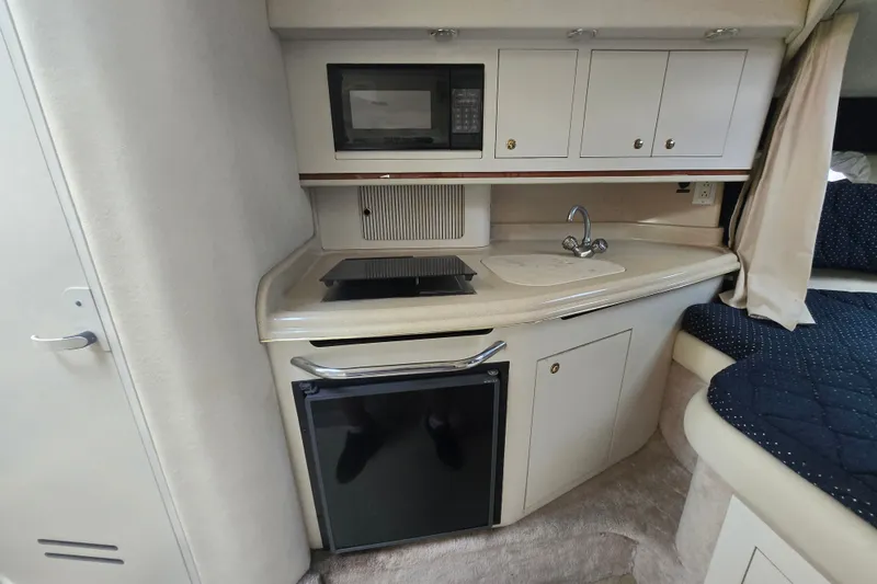 Slide: The Image of 2000 Sea Ray 290 Amberjack cabin kitchen with microwave, sink, and mini-fridge. - 15