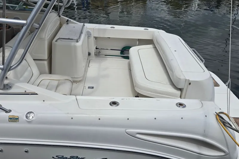 Slide: The Image of 2000 Sea Ray 290 Amberjack boat interior with seating and storage, docked on calm water. - 14