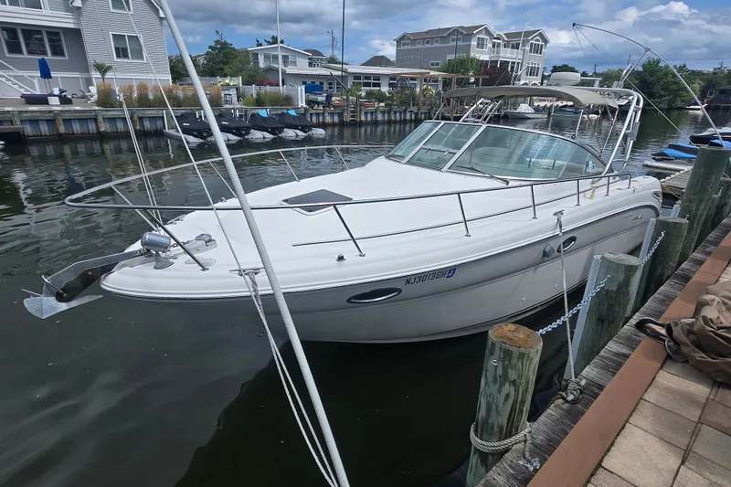 Slide: The Image of 2000 Sea Ray 290 Amberjack boat docked in a marina, surrounded by waterfront homes. - 1