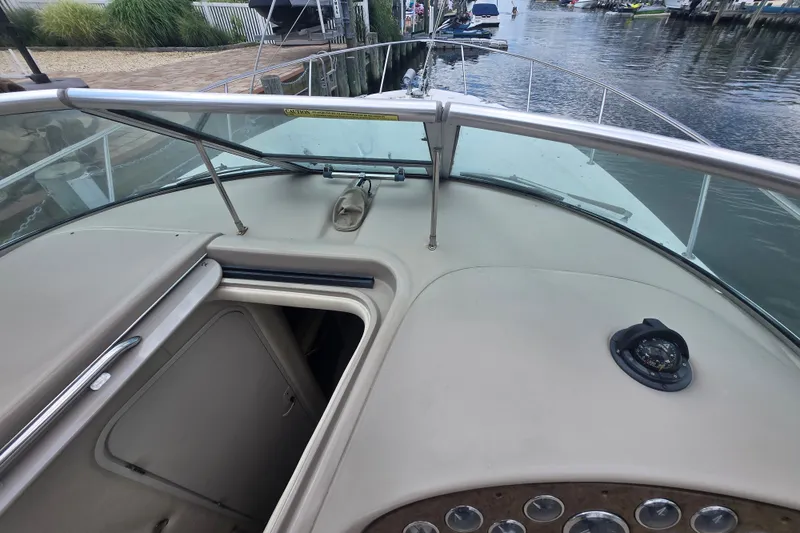 Slide: The Image of 2000 Sea Ray 290 Amberjack boat deck with open hatch and compass, docked by the water. - 25