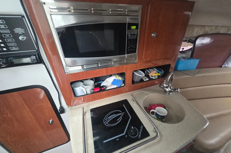 Slide: The Image of 2014 Crownline 264 CR boat interior with microwave, stove, and sink in compact kitchen area. - 22