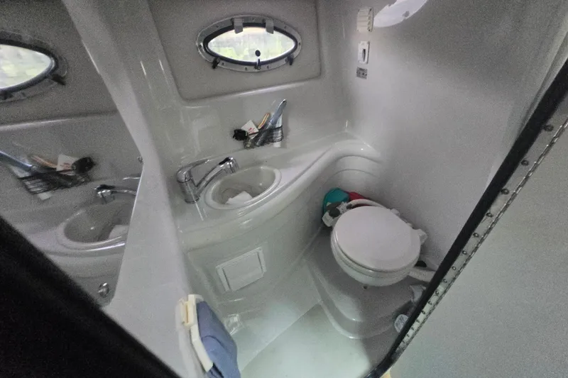 Slide: The Image of 2014 Crownline 264 CR boat bathroom with sink, toilet, and porthole window. - 25