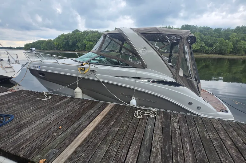 The Image of 2014 Crownline 264 CR boat docked on a wooden pier, surrounded by lush greenery. - 0