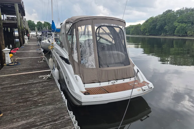 Slide: The Image of 2014 Crownline 264 CR boat docked by a wooden pier on a calm river. - 1
