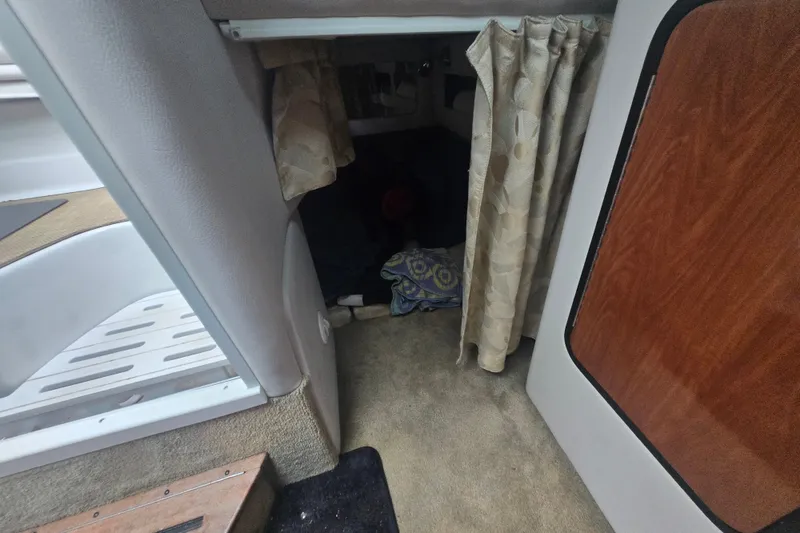 Slide: The Image of Interior cabin view of a 2014 Crownline 264 CR boat with curtains and carpeted flooring. - 20