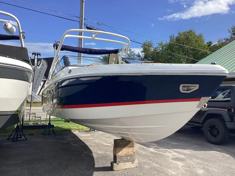 The Image of A 2027 Cobalt R26 boat on a stand. It features a blue hull with a red stripe. - 1
