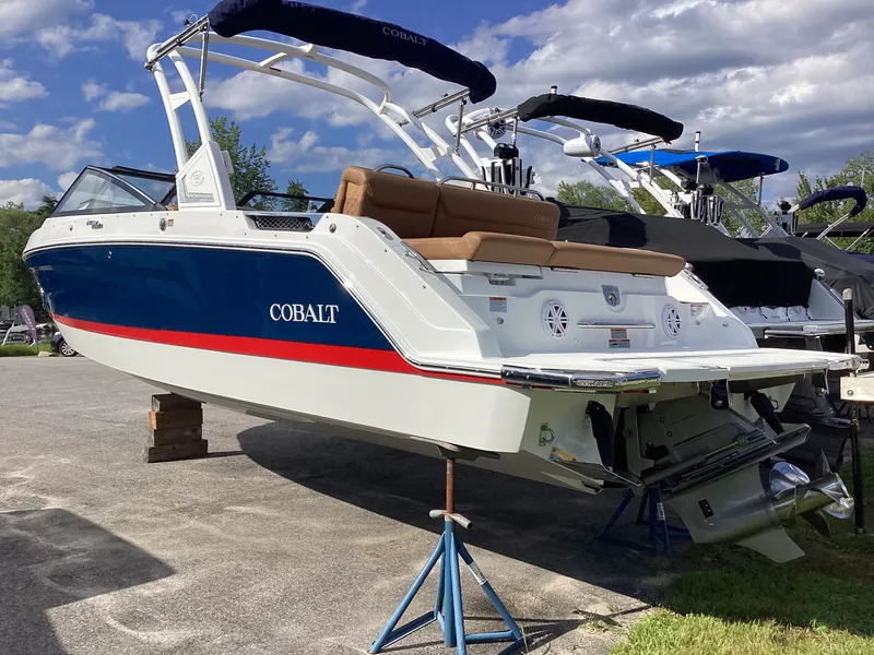 Slide: The Image of A 2027 Cobalt R26 boat on a stand. It features a blue and white design. - 2