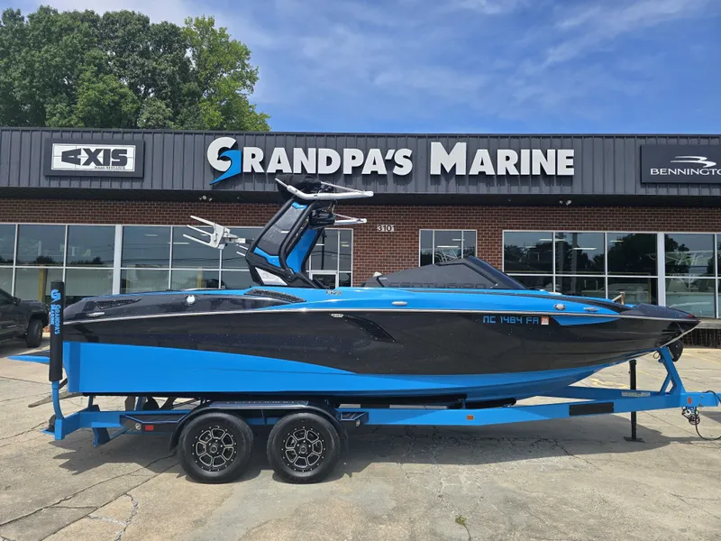 The Image of A blue and black 2022 Centurion Fi23 boat on a trailer in front of a marine store. - 0
