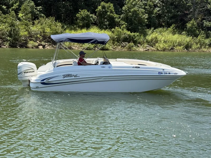 The Image of A white boat cruising on a calm river, featuring a blue sunshade and an outboard motor. - 1