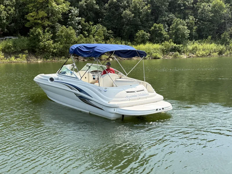 Slide: The Image of A white 2000 Sea Ray 240 Sundeck boat on a calm lake with a wooded shoreline. - 6