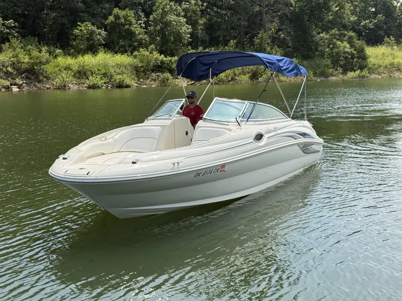 Slide: The Image of A white 2000 Sea Ray 240 Sundeck boat with a blue sunshade on a calm lake. - 13