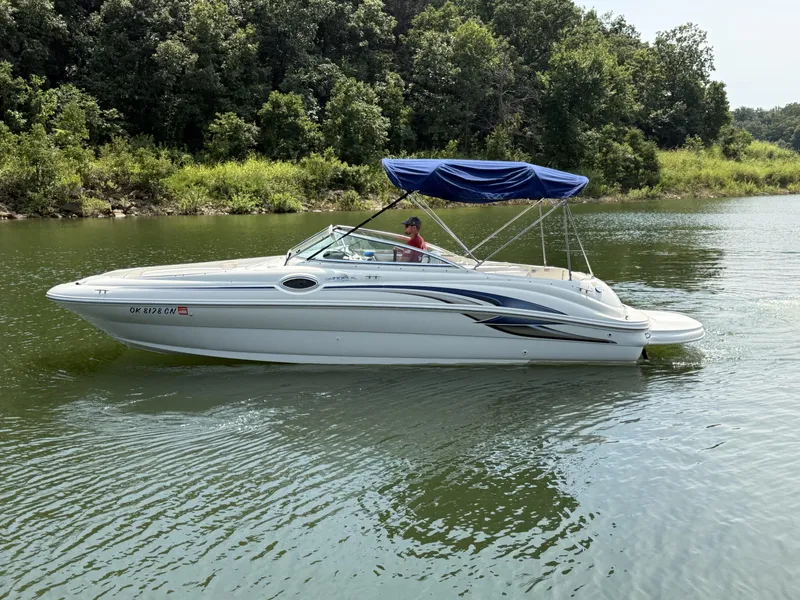 The Image of A white 2000 Sea Ray 240 Sundeck boat cruising on a calm river with a green landscape. - 1