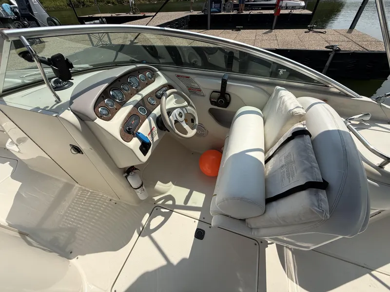 Slide: The Image of The image shows the cockpit of a 2000 Sea Ray 240 Sundeck boat. It features a white steering wheel and a dashboard with multiple gauges. An orange ball is on the floor. - 16