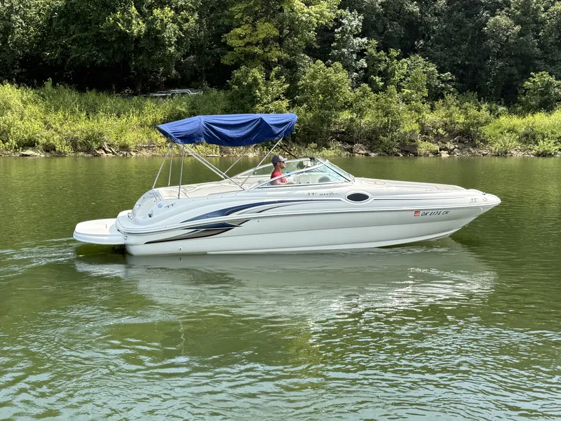 Slide: The Image of A white 2000 Sea Ray 240 Sundeck boat with a blue sunshade cruising on a calm river. - 9