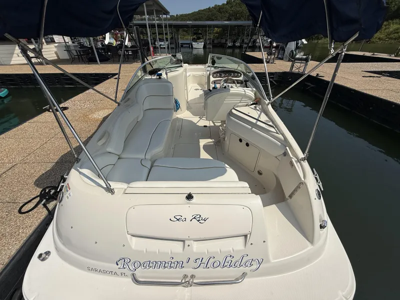 Slide: The Image of A 2000 Sea Ray 240 Sundeck docked. It features white upholstery and an open cockpit. - 19