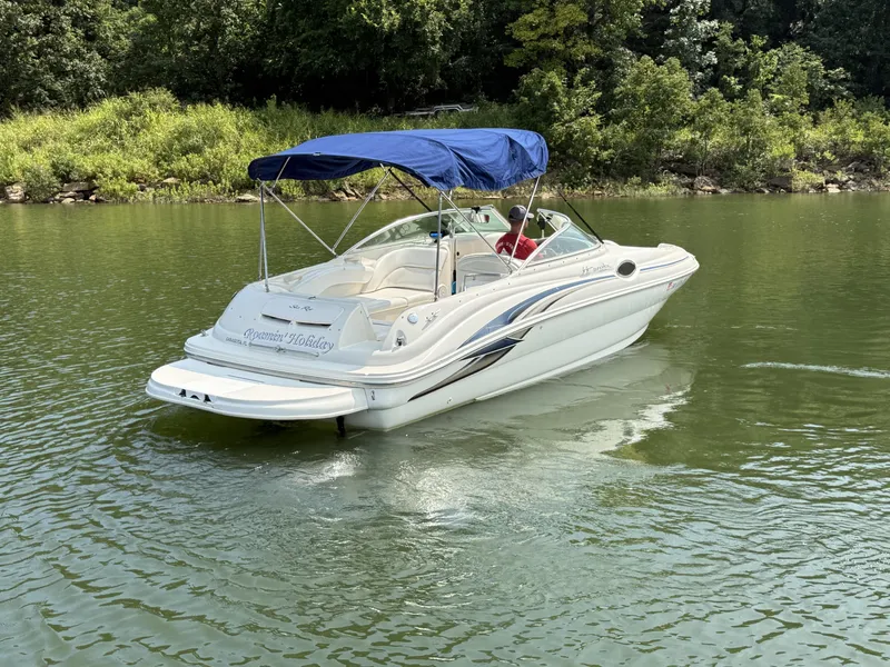Slide: The Image of A white 2000 Sea Ray 240 Sundeck boat with a blue sunshade on a calm lake. - 4