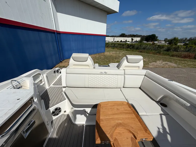 Slide: The Image of The image shows the cockpit of a 2025 Sea Ray SDX 290 with white upholstery and a wooden table. - 20