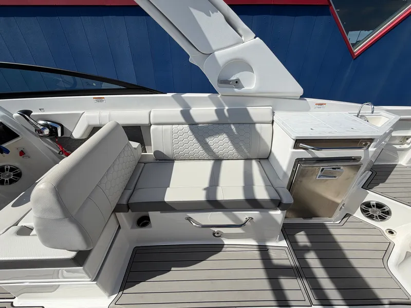 Slide: The Image of The image shows the cockpit of a 2025 Sea Ray SDX 290 with white upholstery and a small kitchenette. - 16