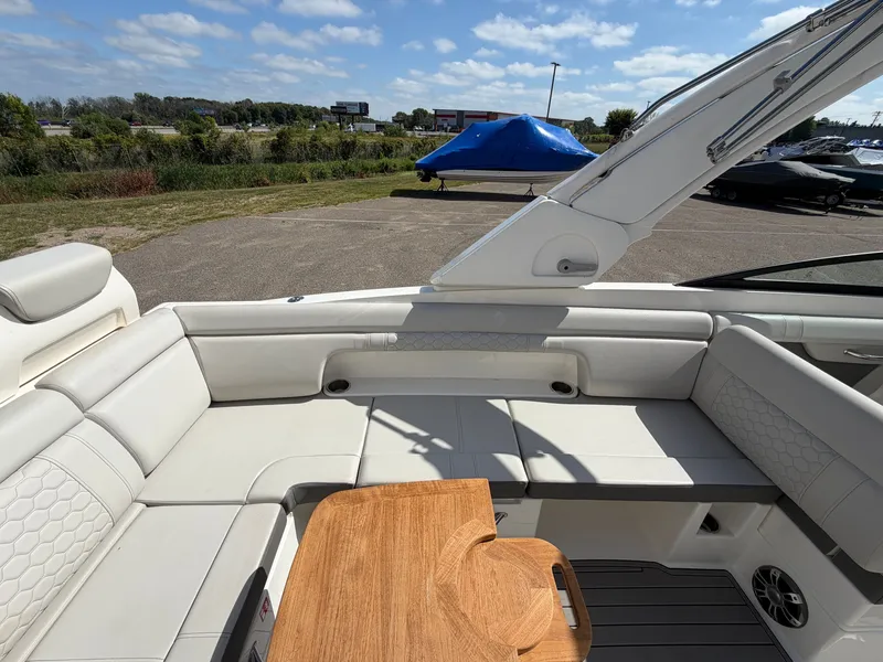 Slide: The Image of The image shows the cockpit of a 2025 Sea Ray SDX 290 with white upholstery and a wooden table. - 23